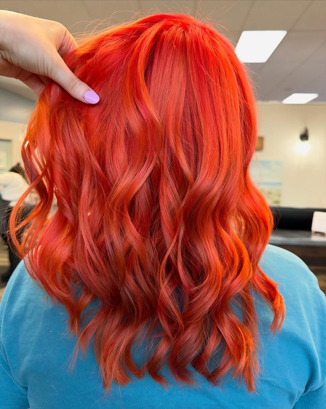 Vivid fiery orange hair color created at Coastal Roots Hair Salon